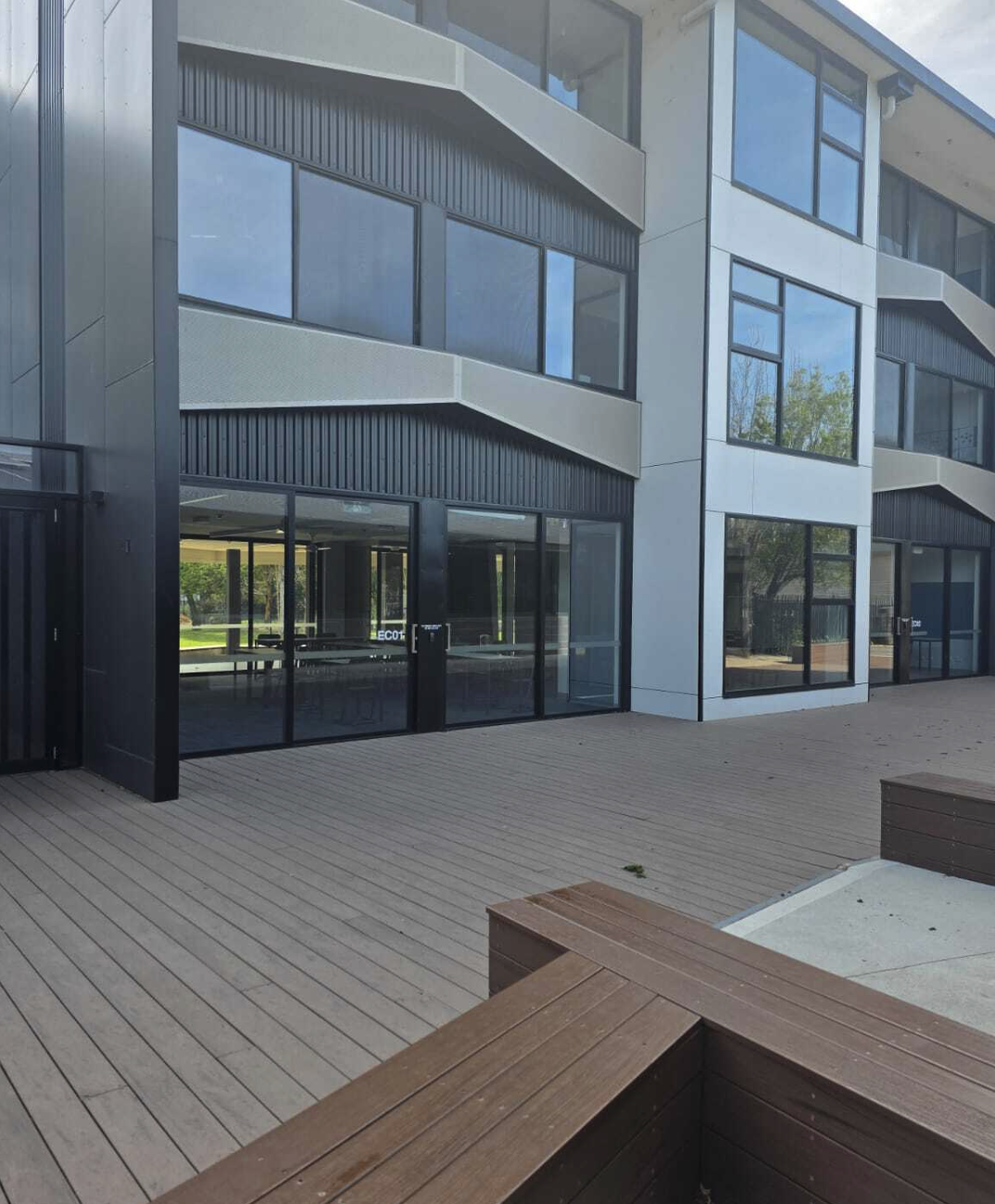 Modern school building exterior with timber deck seating